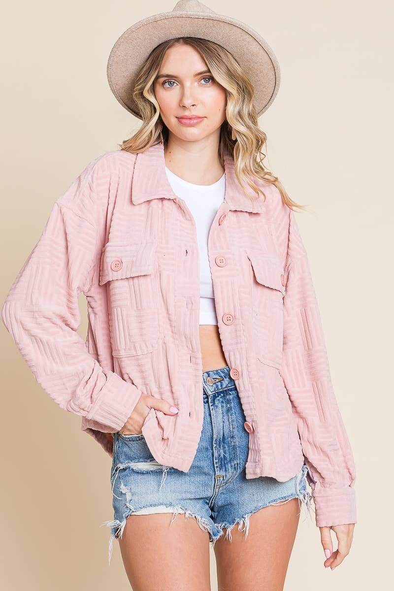 Women's pink embossed shacket with relaxed sleeves, styled with shorts and a hat, perfect for casual wear.