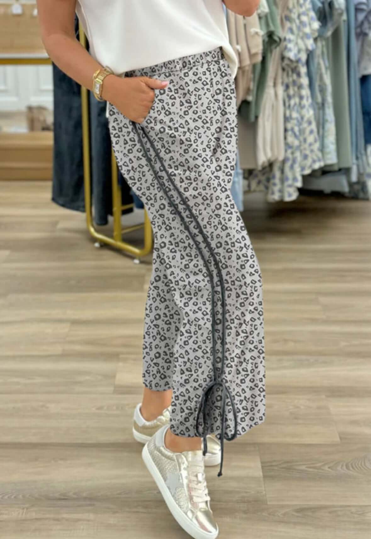 Model wearing SPOTTED SPIRIT PANTS with a playful leopard print, styled with a casual white top and trendy sneakers.
