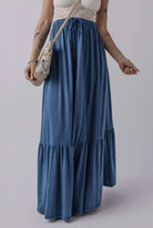 Model wearing FLY WITH ME maxi skirt in blue with tiered design and drawstring waist, perfect for casual summer outfits.