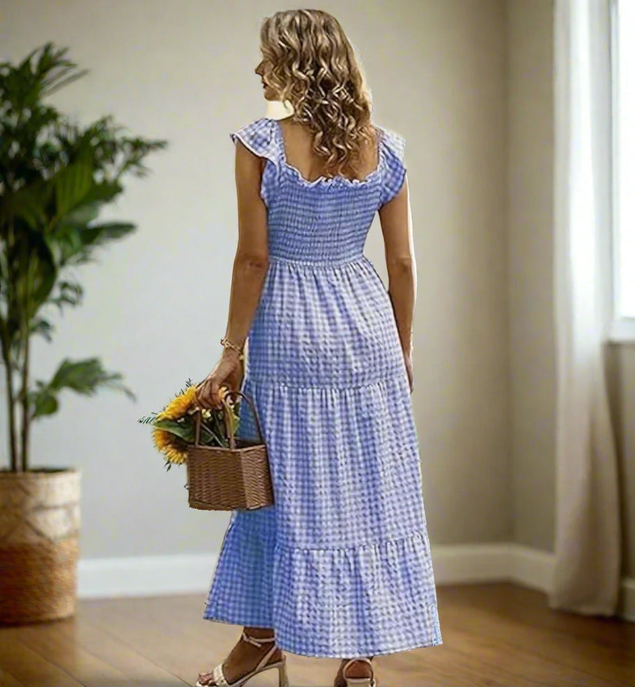 Back view of a woman in a blue gingham smocked sundress, holding a basket of sunflowers.