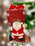 Santa's stocking made of red burlap and plaid, filled with gifts for a festive holiday display.