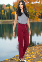 Crimson high rise joggers by Judy Blue styled casually with a gray top and sneakers in an autumn lakeside setting.