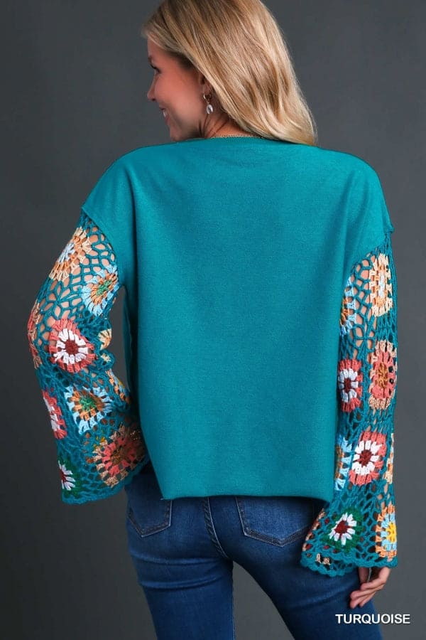 Woman wearing turquoise Flower Child Crochet Sleeve Top with colorful hand-knit crochet sleeves and raw hemline.