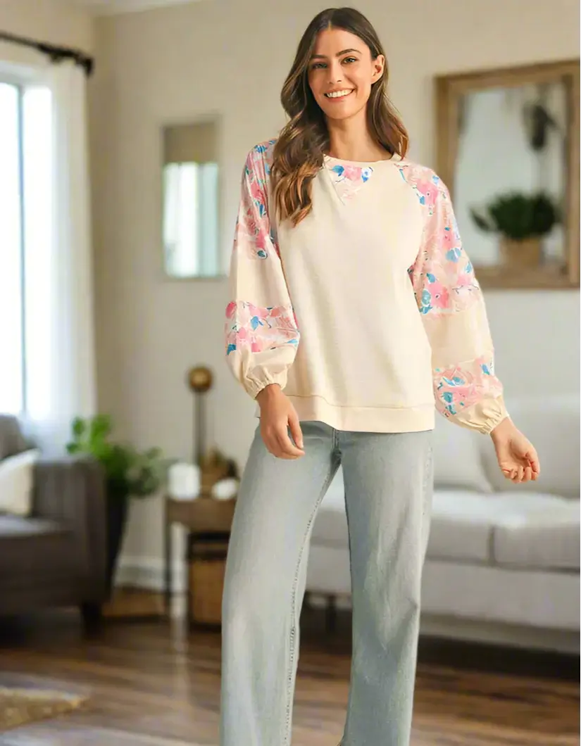 Elegant vanilla ribbed top with floral patchwork sleeves, styled with wide-leg jeans in a cozy interior setting.