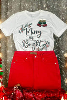 White Merry and Bright tee with holly trim by Bella Canvas, paired with red pants on festive background.