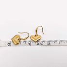 Forever Yours Earrings showcased with a ruler, featuring polished gold heart drops for a romantic touch.