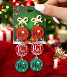 Festive HO HO HO earrings with gold-tone bow and colorful Christmas balls, perfect for adding holiday cheer to any outfit.