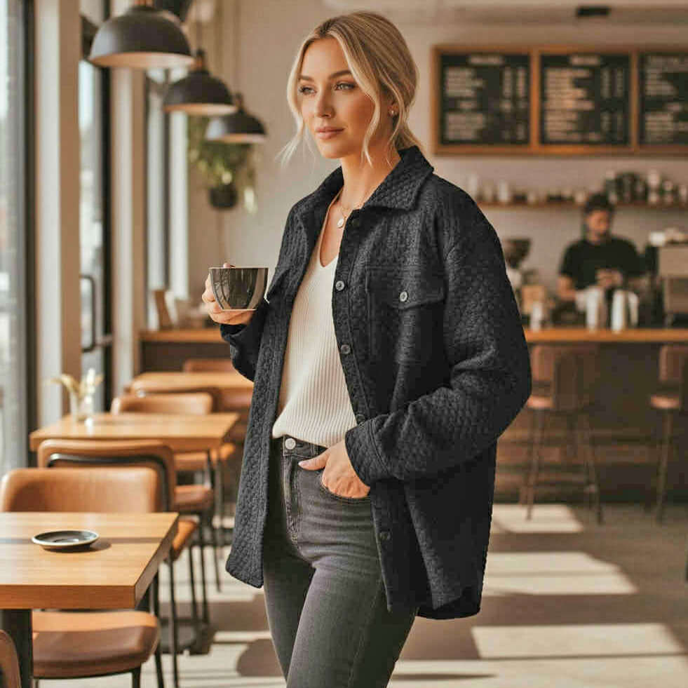 Woman wearing WARM IMPRESSIONS BUTTON DOWN shacket, holding a coffee cup in a stylish cafe setting.