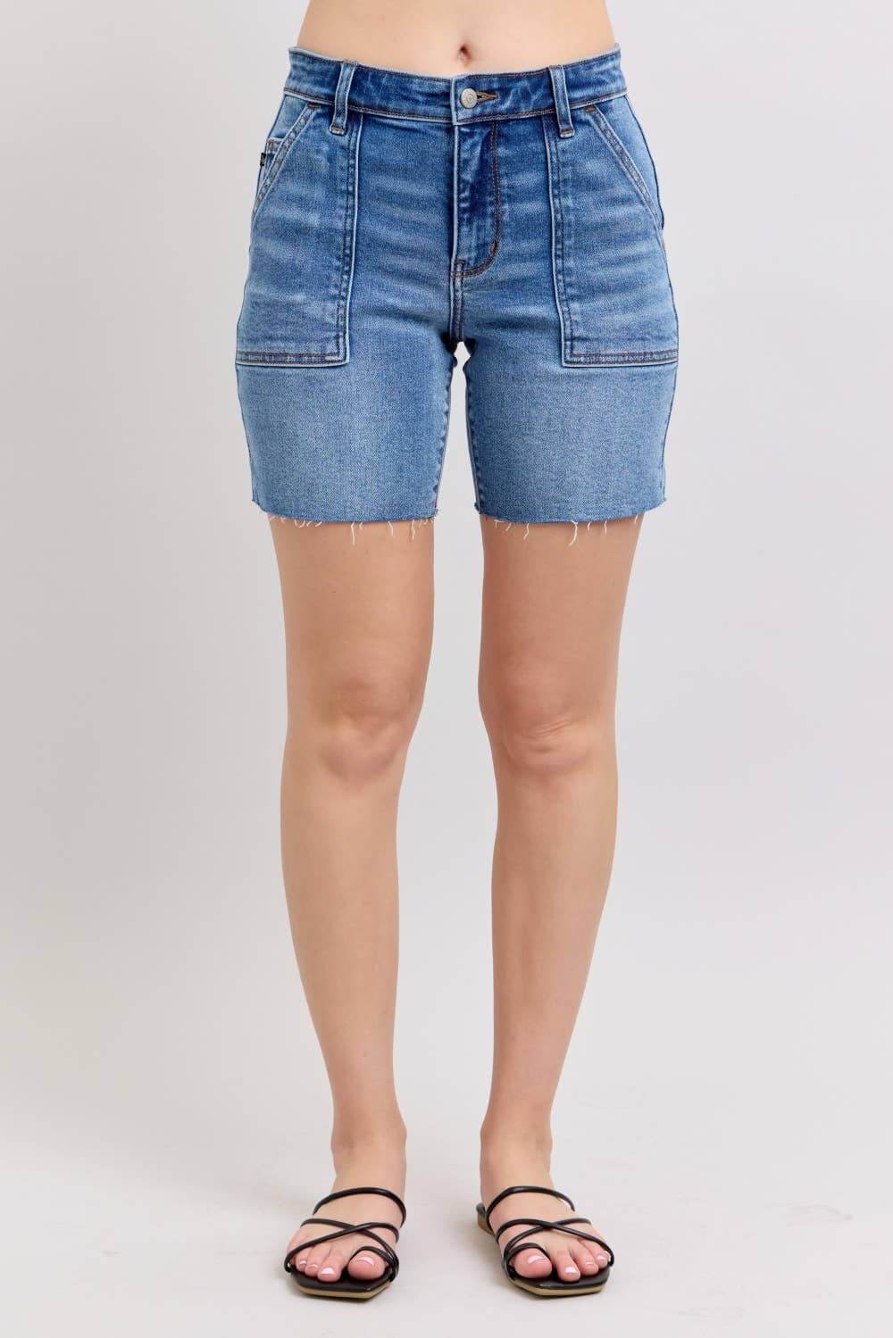JUDY BLUE MIDRISE DAKOTA SHORTS showcasing front view with frayed hem and classic blue denim.