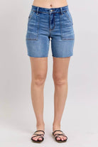 JUDY BLUE MIDRISE DAKOTA SHORTS showcasing front view with frayed hem and classic blue denim.