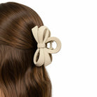 DAILY DARLING BOW HAIR CLIP (6 colors) in a stylish beige color on brown hair, perfect for everyday wear.