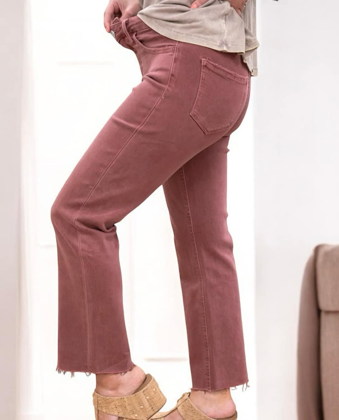 Woman wearing REESE Jeans from Lovervet by Vervet with a high-rise waist, cropped length, and clean cut raw hem in a stylish pink color.