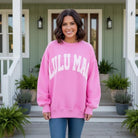 Model wearing LULU MAC Taffy with Pink Puff Logo Crew sweatshirt on a porch with greenery.