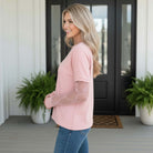 Woman wearing SIMPLY ENCHANTED TOP (pink) with lace mesh sleeves, standing outdoors, showcasing a chic style.