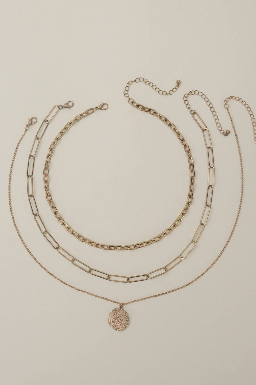 Three-piece multi-layer chain necklace set in gold, featuring a pendant and various chains, perfect for elegant accessorizing.