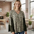 Model wearing UNTAMED SPIRIT TOP (Chai Latte) featuring leopard print and ribbed accents in a cozy indoor setting.