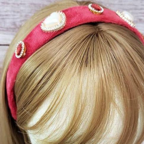 Heart pearl embellished headband displayed on a mannequin, featuring assorted heart designs and a pink band.