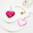 Valentine's Day heart shape pendant necklaces in pink hues displayed on a white surface, perfect for gifting.