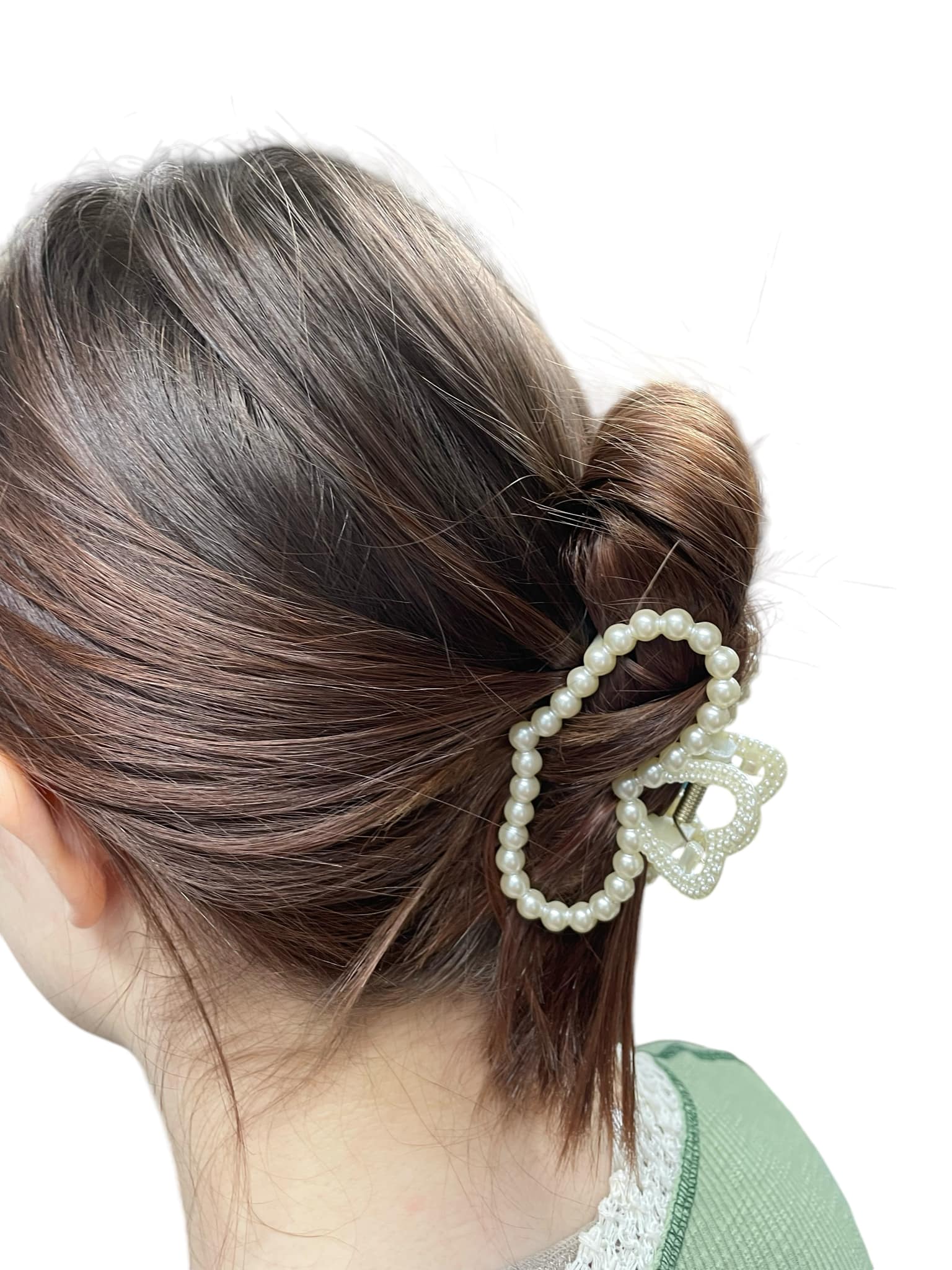 Woman with brown hair wearing a Pearl Perfection Hair Clip styled in a bun, showcasing elegant imitation pearl embellishments.