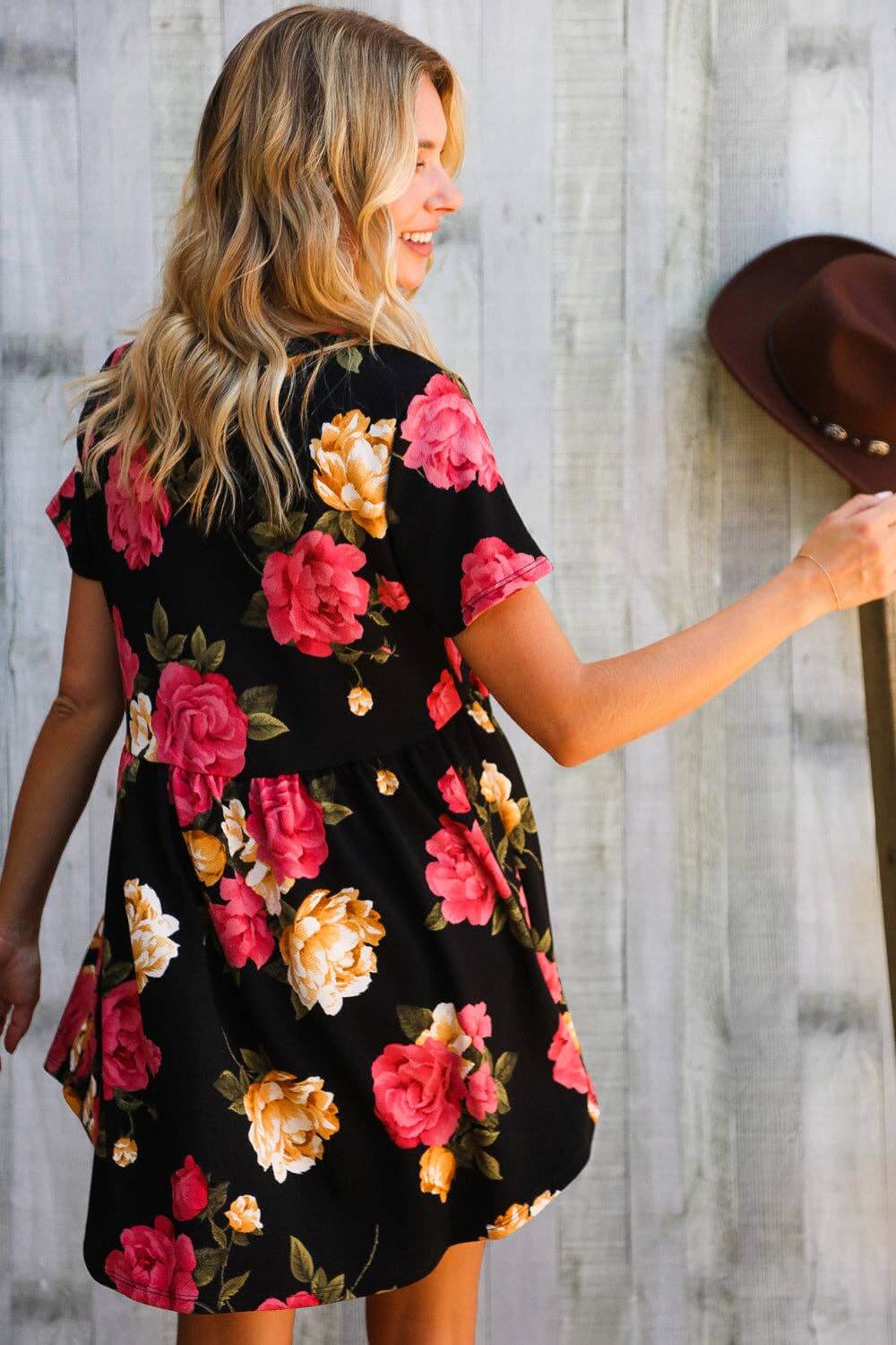 Back view of a woman in a floral Twilight Garden Party Dress with black fabric and colorful blooms.