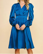 Elegant blue midi dress with surplice bodice, long sleeves, and front skirt slit, showcasing timeless style and comfort from Teal Tiger Boutique.