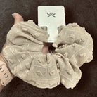 Cloud Comfort Scrunchie in beige with pom-pom texture, perfect for stylish hair ties or wrist accessories.