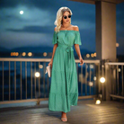 Model wearing ON THE DOT MAXI DRESS in green with polka dots, styled off-the-shoulder for a chic evening look.