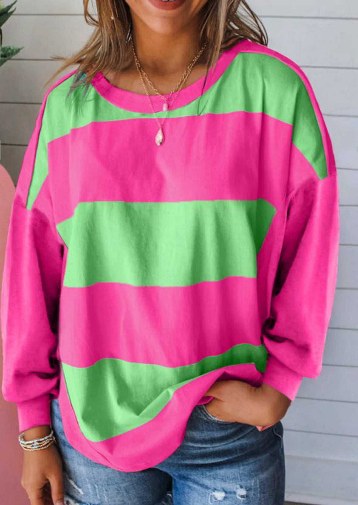 Vibrant pink and green striped top with crew neck and drop shoulder design, perfect for layering and adding playfulness to any outfit.