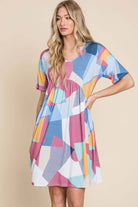 DA1519 Shirred Waist Dress with pleated babydoll style, rounded neckline, mid-thigh length, and colorful geometric pattern.