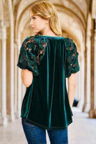 Woman wearing QUIET JOY Velvet Top by Umgee in dark teal green with lace sleeves, showcasing the luxurious velvet fabric.