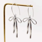 REFIEND RIBBON EARRINGS (2 colors) featuring a polished silver bow-inspired drop design.