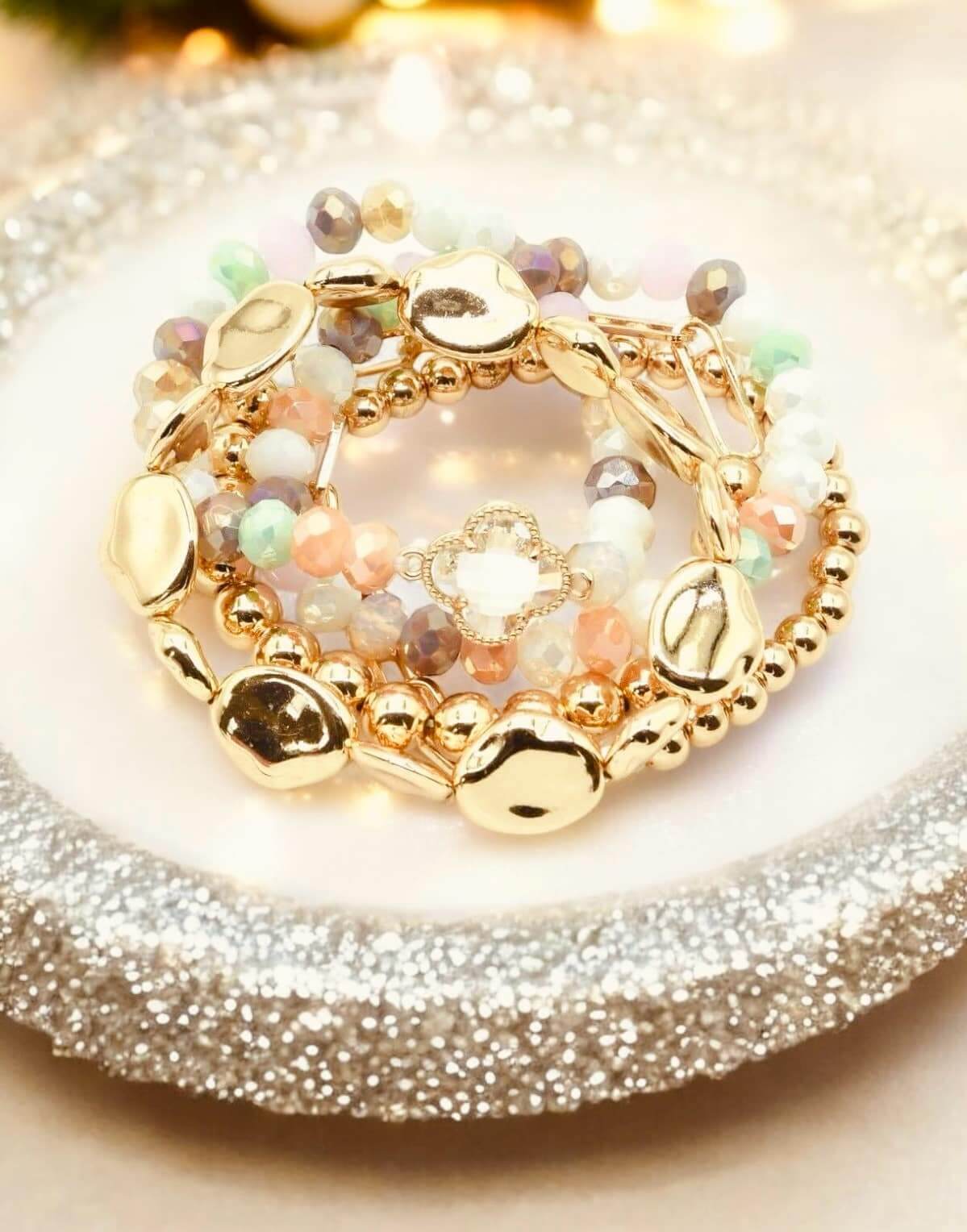 Serene Bracelet Set by Nine Jewelry, featuring gold-toned quatrefoil stretch bracelets in pastel colors.