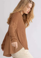 Woman wearing cinnamon Free and Easy Top by UMGEE with crochet yoke and long sleeves, showcasing flowy design and linen contrast back.