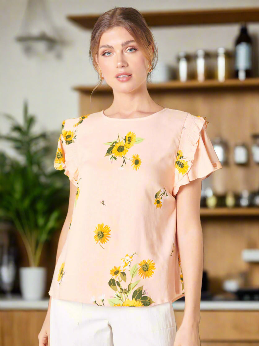 Blush yellow DAISY MARIE TOP from SugarLips with sunflower print and ruffle sleeves, styled for a spring look.