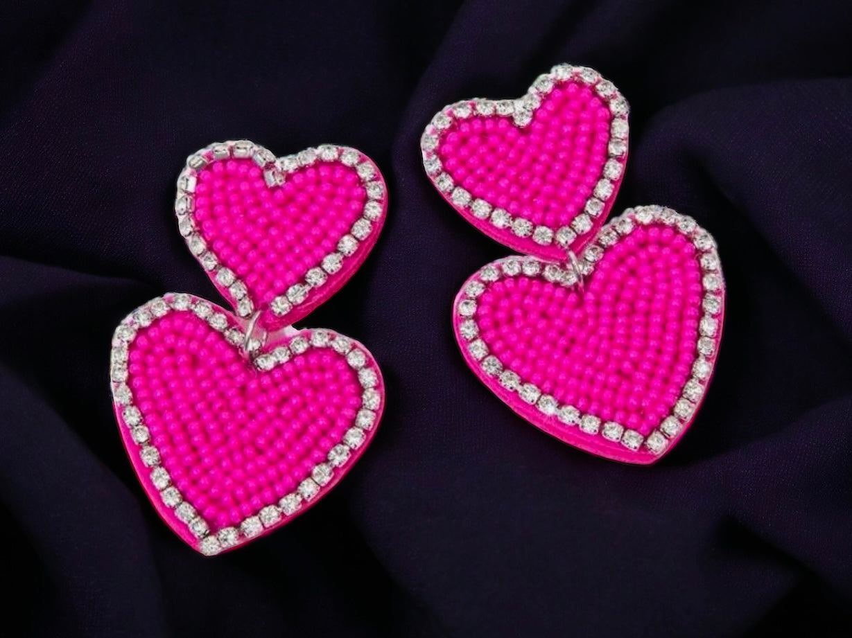 Hot pink beaded heart earrings with rhinestone trim, perfect for adding a vibrant touch to any outfit.