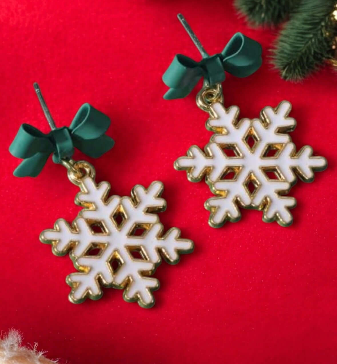 Winter Wonderland Snowflake Earrings with green bow on red background, perfect for holiday outfits.