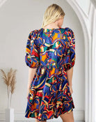 Woman wearing vibrant abstract print dress by TCEC, back view, puff sleeves, in stylish interior setting.