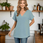 Woman wearing a dusty blue Air Kiss Top by Zenana with V-neckline and high-low hem, styled with jeans.