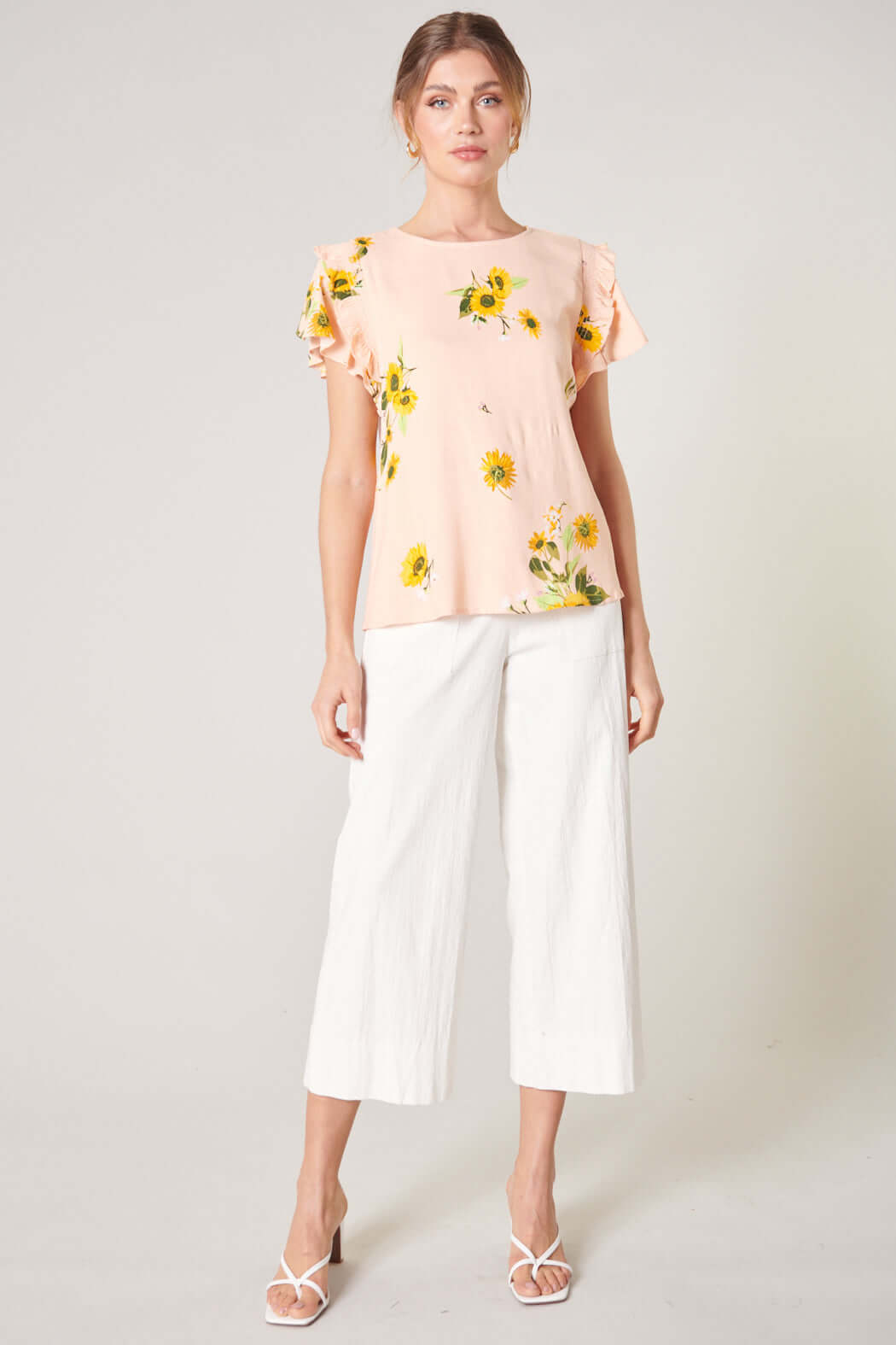 Blush yellow Daisy Marie top with sunflower print, paired with white cropped pants for a stylish spring look.