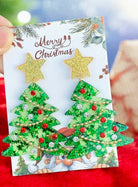 Star On Top Christmas Tree Earrings featuring green trees with gold stars and festive rhinestones on a Christmas card backdrop.