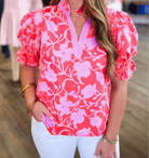 Model wearing the Society Sweetheart Top, featuring pink floral design and puff sleeves, styled with white pants.