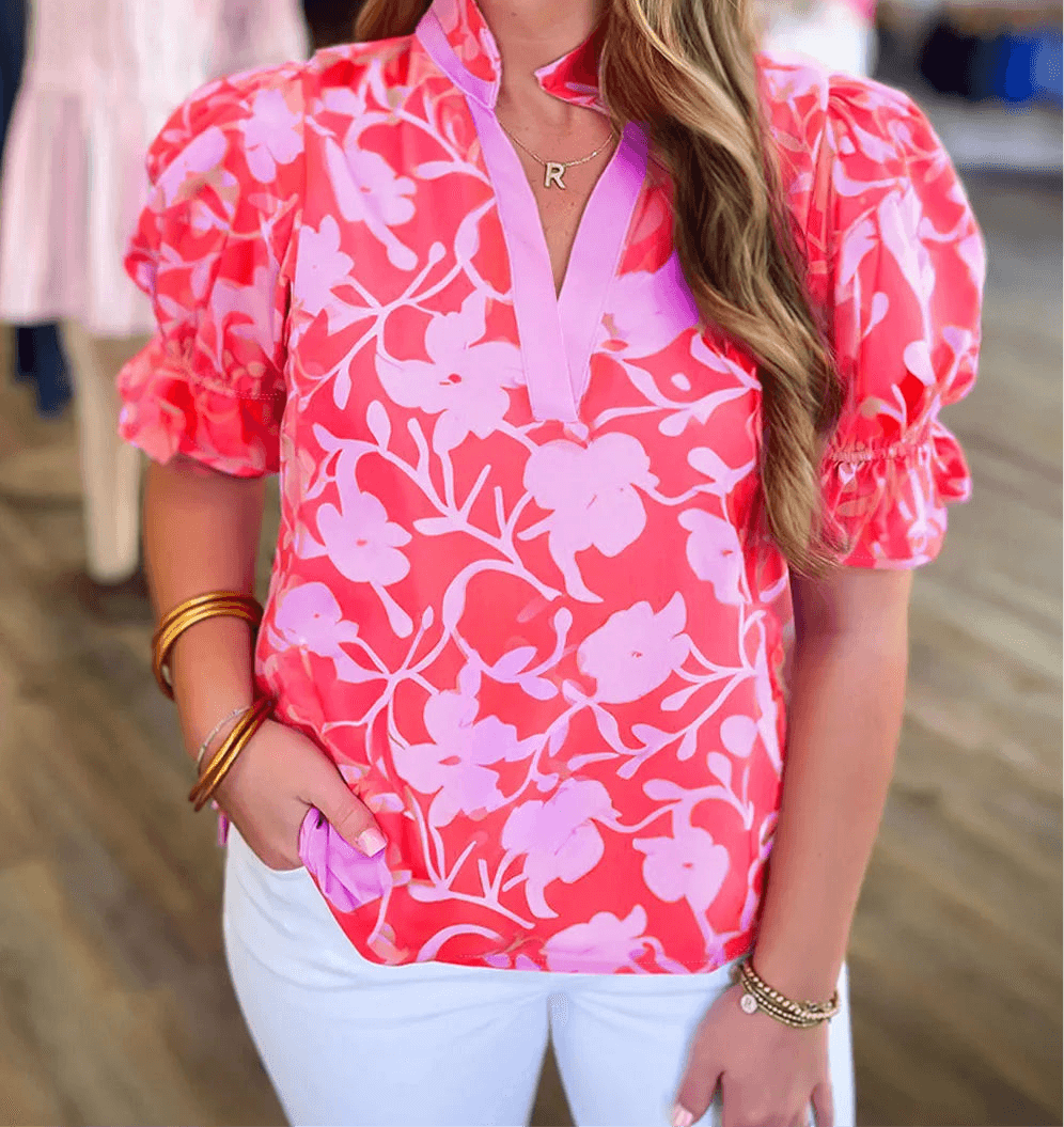 Model wearing the Society Sweetheart Top, featuring pink floral design and puff sleeves, styled with white pants.