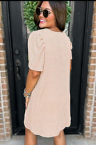 Back view of woman wearing beige Carefree Spirit Dress with puff sleeves and pockets, styled with sunglasses.