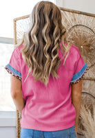 Back view of a woman in a taffy pink Pure Instincts Top with colorful sleeves and leopard patchwork detailing.