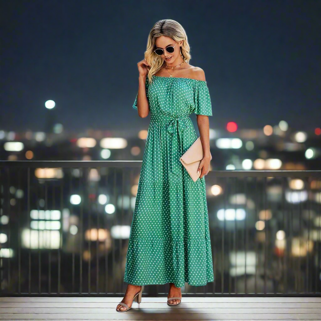 Woman in a green polka dot maxi dress, styled off-the-shoulder with ruffles and a belt, perfect for casual occasions.