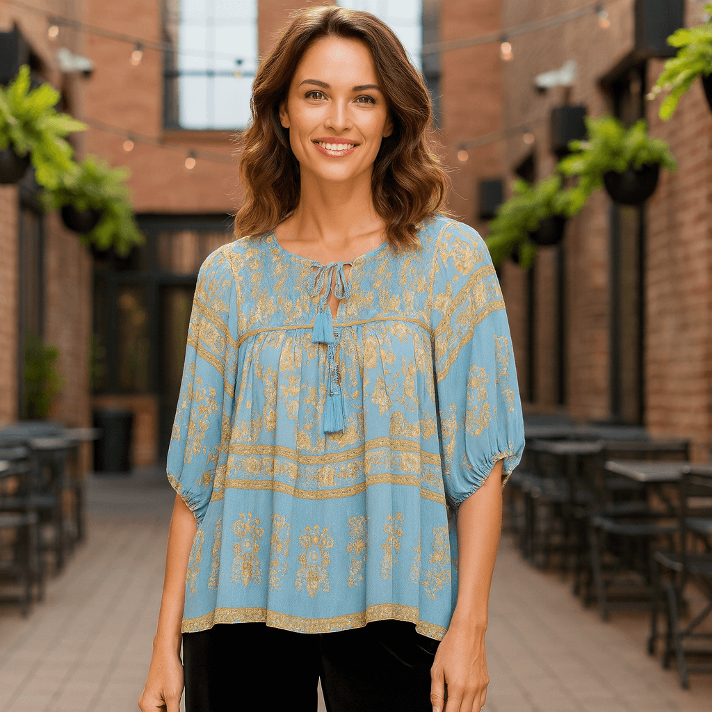Model wearing TUSCAN DREAM Top - UMGEE in blue with golden print and tassel ties, perfect for boho style.