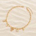 Gold tone Coastal Darling Charm Necklace featuring a heart, star, seashell, and ribbon bow on a paperclip chain.