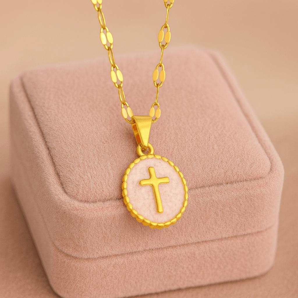 Gold-tone cross pendant necklace on soft pastel display, perfect for adding elegance to any outfit.