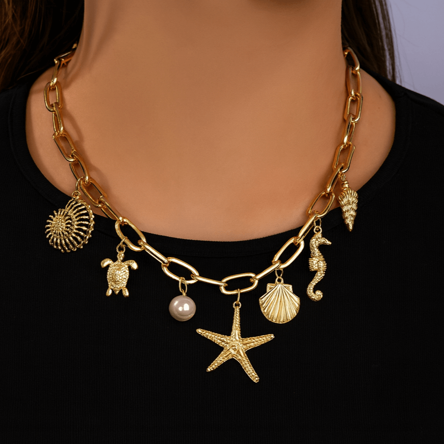 Beautiful gold tone Star of the Sea charm necklace featuring turtle, scallop, pearl, seahorse, and starfish charms.