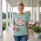 Woman holding coffee cup wearing LULU MAC- OCD TEE IN DUSTY MINERAL WASH BLUE on porch.